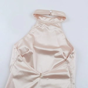 Détail d'une robe dos nu en satin champagne avec décolleté licou et fermeture à bouton