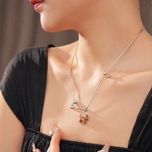 Gros plan d'un collier pendentif cheval à bascule en bois minimaliste porté par un mannequin