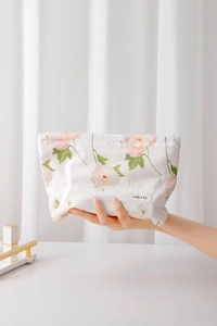 Dettaglio beauty case in cotone floreale con texture a pois e etichetta tessuta