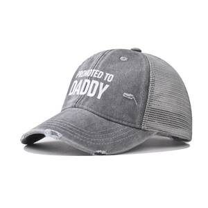 Macro detail of washed grey mesh cap featuring white Promoted to Daddy print and distressed brim