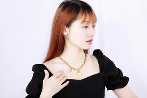 Dettaglio di una collana a catena dorata con pendente quadrato e chiusura OT su modella