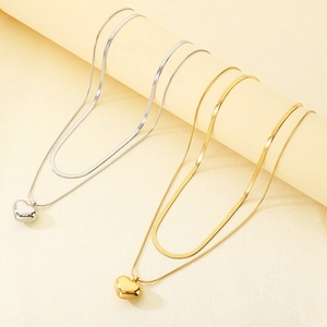 Detail of layered gold and silver heart necklaces with polished snake and flat chains