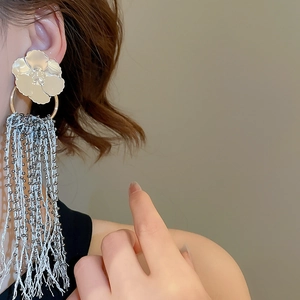 Detailed close-up of floral tassel earrings with silver bead chains on a model