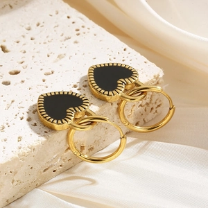 Detailed close-up of golden heart earrings with black enamel on a silk background