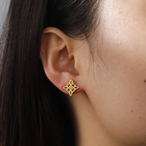 Hollow witch knot S-shaped gold earrings in stainless steel on a female model