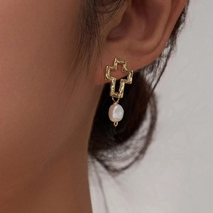 Boucles d'oreilles croix évidée en argent S925 avec perle naturelle sur mannequin femme