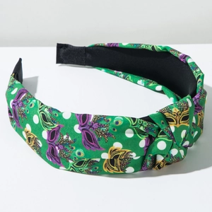 Detail of green fabric headband featuring purple carnival masks and white polka dots