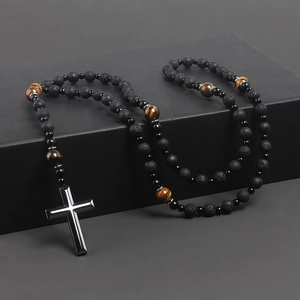 Detail of cross pendant necklace with natural volcanic rock and tiger eye stone beads