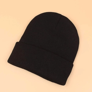 Detailed close-up of a black knitted beanie featuring soft ribbed texture and cuffed design