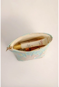 Detail view of open blue jacquard makeup bag with floral embroidery and gold zipper