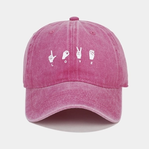 Detail view of pink washed cotton baseball cap with white LOVE hand gesture embroidery