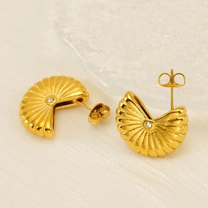 Macro view of gold round stud earrings with geometric stripes and sparkling center zircon