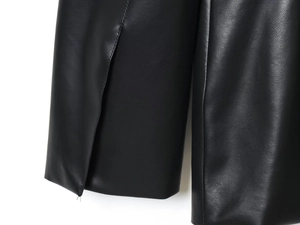 Detailed macro view of black faux leather fabric texture and fine stitching on the jacket cuff