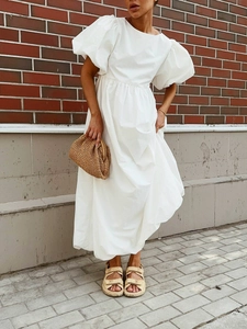 Robe blanche en coton à manches bouffantes avec pochette tissée et sandales sur rue