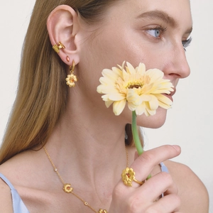 Detalle de cerca de pendientes y anillo florales bañados en oro de 18K con circón