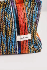 Detail of colorful knitted bohemian makeup bag showing vertical stripes and H&R logo