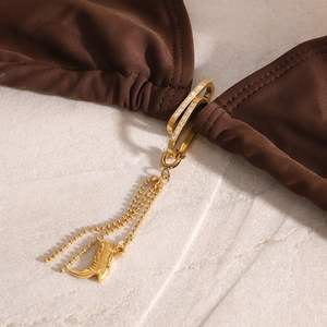 Detailed close-up of golden bikini connector with rhinestones and boot-shaped pendant