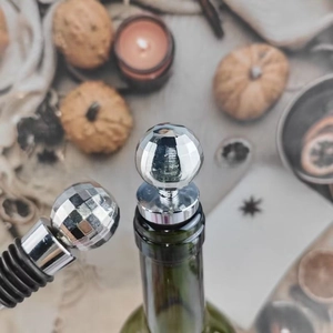 Detail of silver disco ball wine stopper with black rubber seal on a green glass bottle