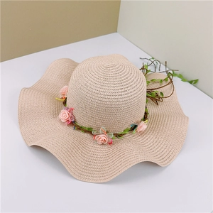 Detailed close-up of a wavy wide-brimmed straw hat with elegant pink floral wreath