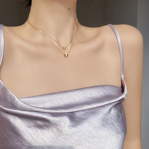 Macro view of double-layer gold chain necklace with round beads on model's neck