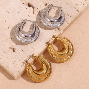 Detailed view of U-shaped gold and silver earrings with textured relief on stone base