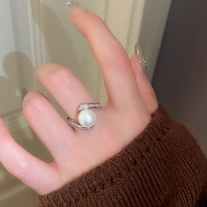 Gros plan d'une bague serpent argentée avec perle et petits diamants sur le doigt