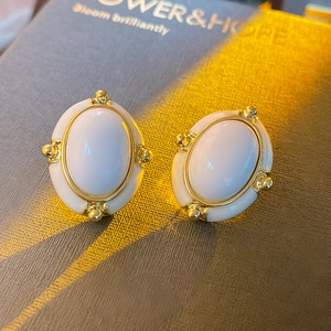 Vintage oval gold-plated earrings with white inlay and beaded edge on grey display box