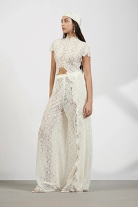 Full view of woman in white lace two-piece set with high waist trousers and headscarf