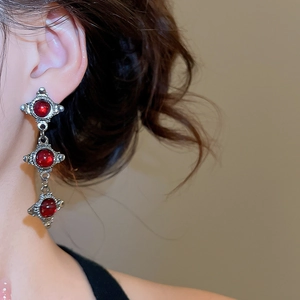 Close-up of retro silver earrings with three red resin beads in a vintage royal style