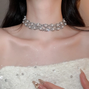 Detail of silver choker necklace with floral rhinestone mesh and teardrop pearls on a model
