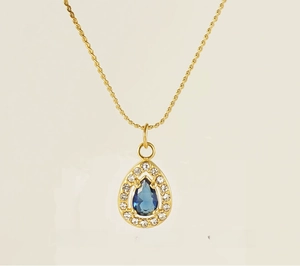 Detailed macro view of 18K gold plated stainless steel teardrop pendant with blue gemstone