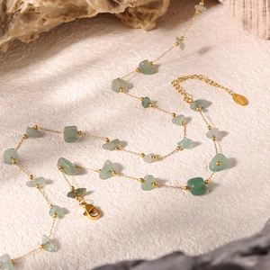 Detail of green natural crushed stones and golden stainless steel beads on a fine chain