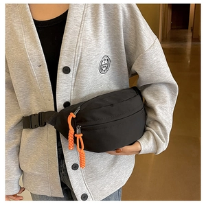 Detail of black canvas waist bag with vibrant orange zipper pull cords and buckle strap