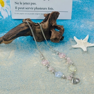 Detailed view of colorful flower beads and silver shell pendant on a beach background