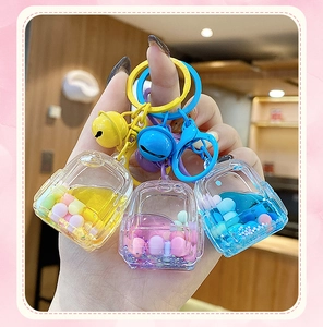 Three colorful liquid sand backpack keychains in yellow, pink and blue with bells