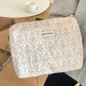 Trousse à maquillage matelassée à fleurs avec fermeture éclair tenue à la main