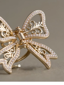 Macro shot of French style gold metal butterfly hair claw with pearl details and spring