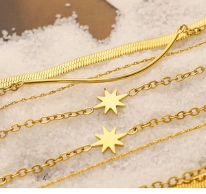 Macro detail of 18K gold-plated snake bone bracelets and star pendants on white crystal