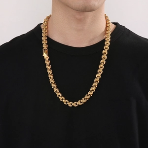 Detailed close-up of a chunky golden punk style necklace on a male model outfit