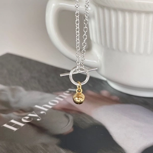 Silver O-chain necklace with gold bell pendant featuring a stylish OT buckle closure