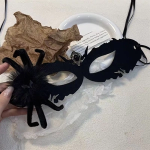 Macro shot of black fuzzy masquerade mask with spider detail and center gemstone