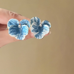 Detailed view of blue iris flower earrings with enamel petals and central crystal accents