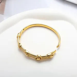 Detailed view of 18K gold plated open bangle with granular texture and floral reliefs