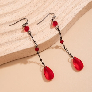 Macro shot of red blood-drop crystal earrings on a natural wood surface background