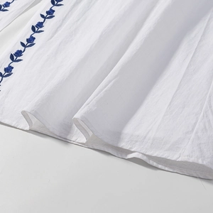 White cotton linen midi dress featuring elegant blue floral embroidery on the hem