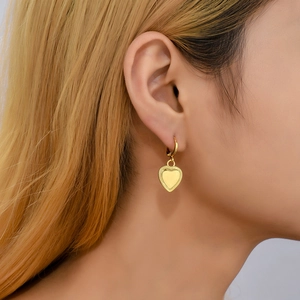 18K gold plated stainless steel heart dangle earrings shown on a female model