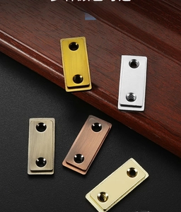 Close-up of magnetic door catch plates in bronze and silver brushed metal finishes
