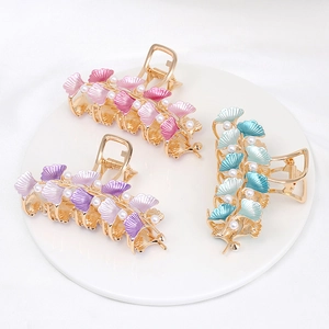 Detailed view of large alloy hair claws with ginkgo leaves and pearls in three colors