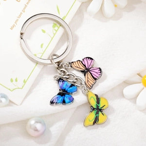 Close-up of colorful enamel butterfly pendants on a silver metal keychain with floral decor