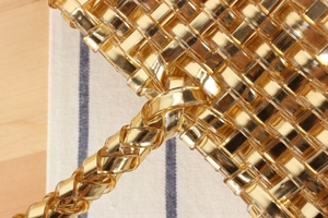 Vue macro d'un sac à main tissé doré montrant la texture métallique et l'artisanat détaillé